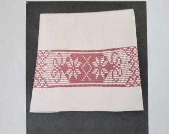 May include: A white towel with a pink embroidered border. The embroidery features a repeating pattern of stylised flowers. The text "Huck Embroidery Towel Pattern © Stitch On It Direct 2018" is printed above the towel. The text "Easy to Read Pattern With Complete Instructions." is printed below the towel.