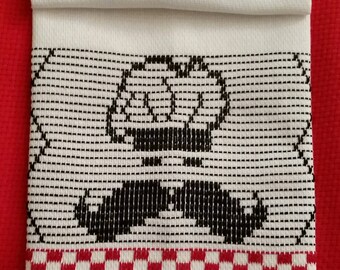 May include: A white kitchen towel with a black embroidered design of a moustache and a crown. The towel has a red and white checked border.