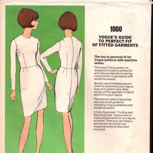 May include: A vintage Vogue sewing pattern envelope, number 1000, featuring a guide to fitting garments. The illustration shows two views of a long-sleeved, knee-length dress in white. Text includes Vogue's Guide to Perfect Fit of Fitted Garments.
