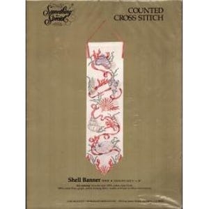 May include: A counted cross-stitch kit featuring a shell banner design. The banner is white with red and pink seashell and ribbon motifs. The packaging includes the text "Something Special" and "Shell Banner". The banner measures 4 x 14 inches.
