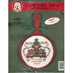 May include: A Christmas Skillet counted cross stitch kit. The kit includes a red skillet-shaped frame with a stitched design of two sheep, a Christmas tree, and the text "Christmas warms the heart." The frame measures 5" x 5".