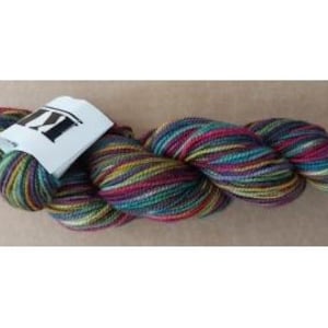 May include: A skein of colorful yarn with a white tag. The yarn features a mix of colors including teal, purple, yellow, and brown. The tag has a black logo. The yarn is likely for knitting or crocheting projects.