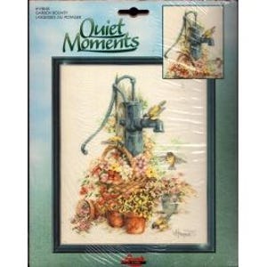 May include: A cross-stitch kit titled "Quiet Moments" featuring a framed image of a water pump surrounded by flowers and birds. The kit includes a smaller image of the design and is packaged in a blue and green cardboard.