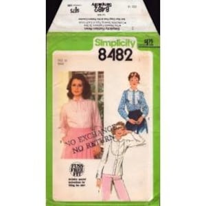 May include: A Simplicity 8482 sewing pattern envelope featuring illustrations of blouses with ruffled collars and button-down fronts. The packaging includes text such as Simplicity 8482, Fuss Free Fit, and a red stamp stating NO EXCHANGE NO RETURN.
