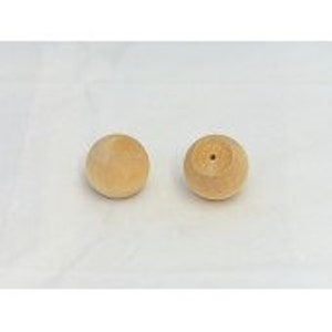 May include: Two small, round, unfinished wooden knobs. One knob has a small hole drilled into the top. The knobs are light brown and sit against a white background.
