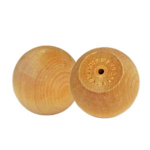 May include: Two light-colored wooden spheres. One sphere is smooth, while the other has a hole in the center and carved details around it. The wood grain is visible on both spheres. These spheres could be used as decorative elements or components in a larger project.