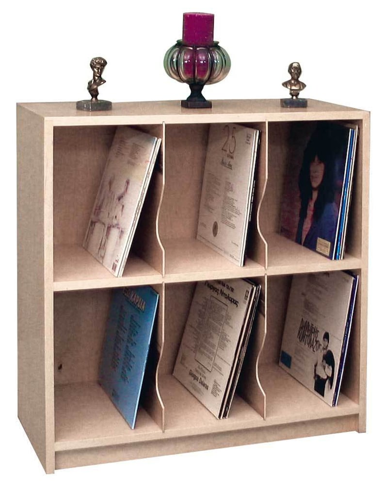 May include: A light wood record storage cabinet with six compartments. Each compartment has a divider to hold vinyl records upright. The cabinet has a shelf on top for displaying decorative items.