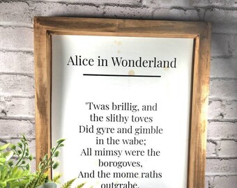 May include: Wooden framed print featuring text from "Alice in Wonderland." The text includes the title, a poem, and the number 73. The frame is a light brown color, and the background is white with some light stains.