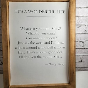 May include: A framed print with a white background and black text. The text reads "IT'S A WONDERFUL LIFE" and includes a quote from the movie: "What is it you want, Mary? What do you want? You want the moon? Just say the word and I'll throw a lasso around it and pull it down. Hey, That's a pretty good idea. I'll give you the moon, Mary. - George Bailey"