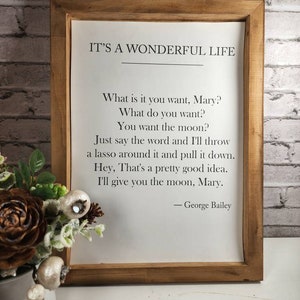 May include: A framed print with a white background and black text. The text reads "IT'S A WONDERFUL LIFE" and includes a quote from the movie. The quote reads: "What is it you want, Mary? What do you want? You want the moon? Just say the word and I'll throw a lasso around it and pull it down. Hey, That's a pretty good idea. I'll give you the moon, Mary." The quote is attributed to "George Bailey".