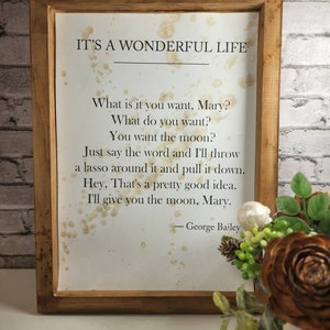 May include: A framed print with a quote from the movie "It's a Wonderful Life." The quote reads: "What is it you want, Mary? What do you want? You want the moon? Just say the word and I'll throw a lasso around it and pull it down. Hey, That's a pretty good idea. I'll give you the moon, Mary." - George Bailey