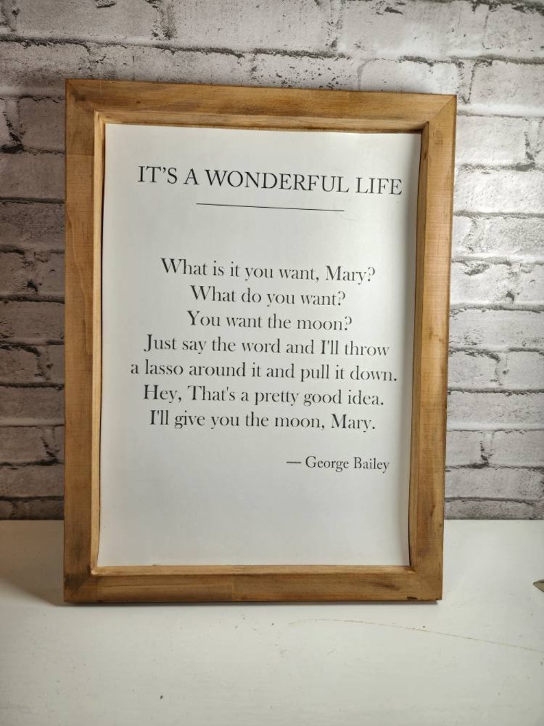 May include: A framed print with a quote from the movie "It's a Wonderful Life." The quote reads: "What is it you want, Mary? What do you want? You want the moon? Just say the word and I'll throw a lasso around it and pull it down. Hey, That's a pretty good idea. I'll give you the moon, Mary." - George Bailey