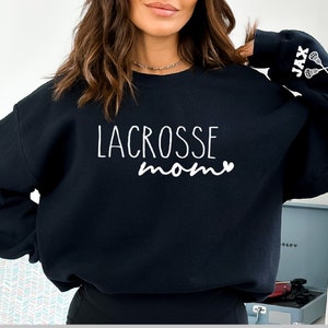 May include: Black sweatshirt with the text "LACROSSE mom" and a heart on the front. The left sleeve has the text "JAX" and two lacrosse sticks.