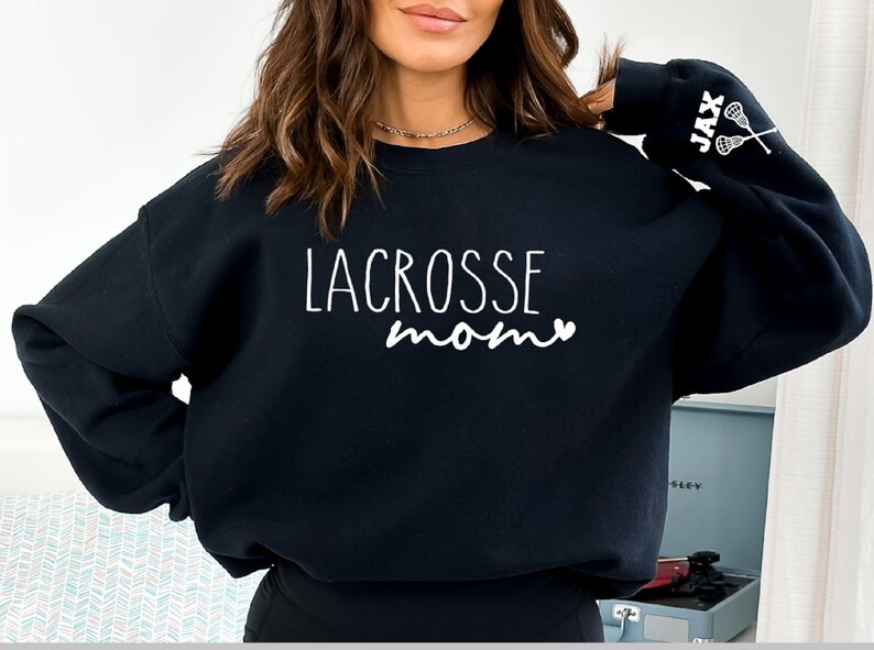 May include: Black sweatshirt with the text "LACROSSE mom" and a heart on the front. The left sleeve has the text "JAX" and two lacrosse sticks.