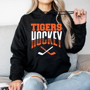 May include: Black hoodie with the text "TIGERS HOCKEY" in orange and white with two crossed hockey sticks in white and orange.