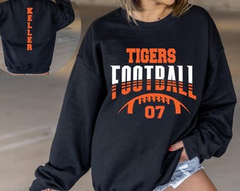 May include: Black sweatshirt with the words "TIGERS FOOTBALL 07" in orange and white lettering. The back of the sweatshirt has the name "KELLER" in orange lettering. The sweatshirt is a crew neck style.