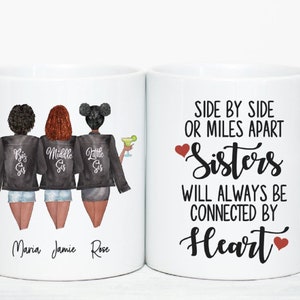 Puede incluir: Taza de cer&aacute;mica blanca con una ilustraci&oacute;n en blanco y negro de tres hermanas con el texto "Big Sis", "Middle Sis" y "Little Sis" en sus chaquetas. La taza tambi&eacute;n tiene el texto "Side by Side or Miles Apart Sisters Will Always Be Connected By Heart" con un coraz&oacute;n rojo a cada lado del texto.