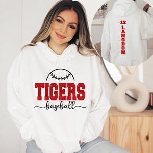 May include: White hoodie with red glitter text that says "Tigers baseball" and a baseball graphic. The back of the hoodie has red glitter text that says "12 LANGDON".