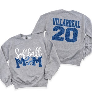 May include: Two grey sweatshirts. One sweatshirt has the text "Softball Mom" in blue glitter with a white baseball graphic. The other sweatshirt has the text "Villarreal 20" in blue glitter.