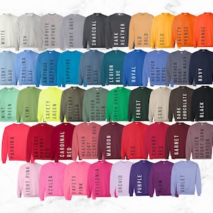 May include: A color chart of 40 different sweatshirt colors. The colors are arranged in rows and columns, with each color labeled with its name. The colors include white, light blue, mint green, paprika, light pink, kiwi, carolina blue, ash, antique cherry, azalea, safety green, graphite, sapphire, military green, cardinal red, safety pink, indigo blue, heather sport green, scarlet red, heliconia, legion blue, charcoal, irish green, maroon, orchid, dark heather red, royal blue, purple, forest green, old gold, cherry red, plum, sand, heather sport royal, garnet, heather dark sport maroon, chocolate, dark navy, orange, and black.