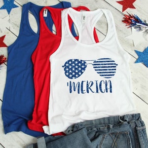 May include: White tank top with a blue and white American flag design of sunglasses and the text 'MERICA'.