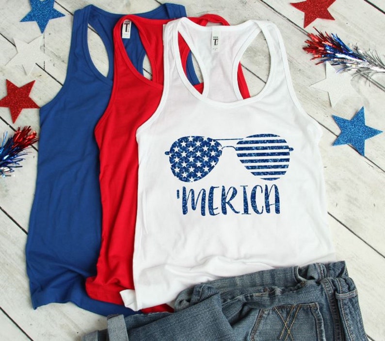 May include: White tank top with a blue and white American flag design of sunglasses and the text 'MERICA'.
