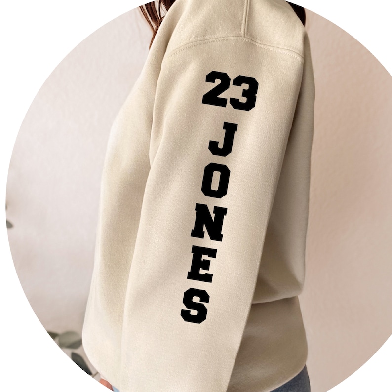 May include: A cream colored sweatshirt with black text on the sleeve that reads "23 JONES".