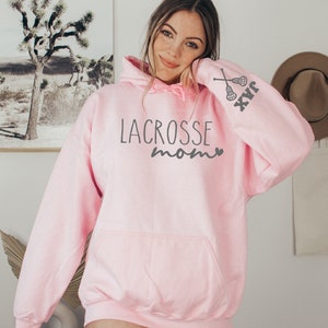 May include: Pink hooded sweatshirt with the text "Lacrosse Mom" and a lacrosse stick graphic on the sleeve.