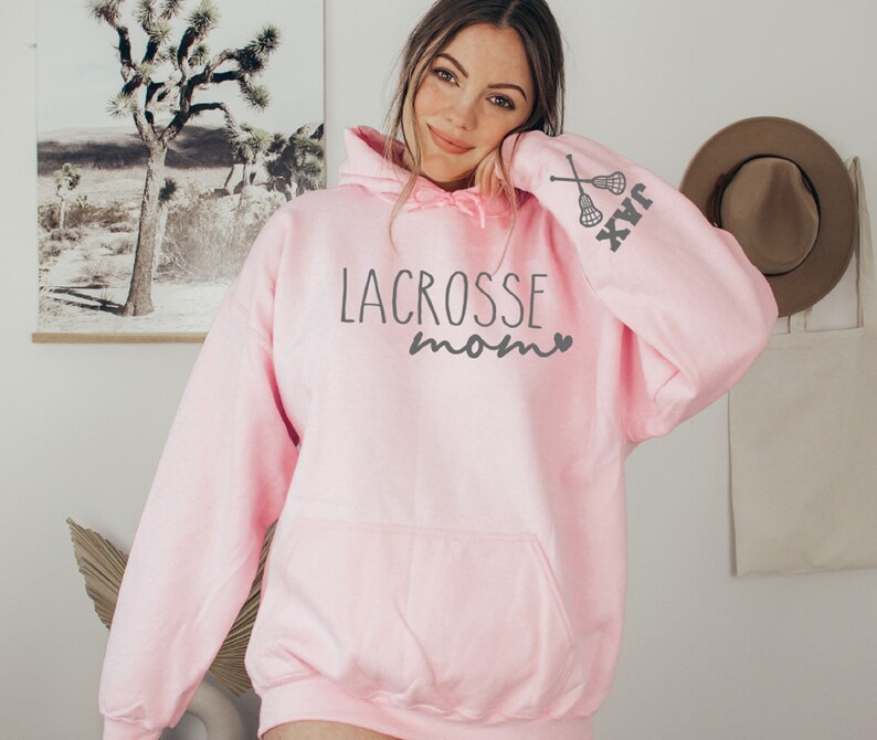 May include: Pink hooded sweatshirt with the text "Lacrosse Mom" and a lacrosse stick graphic on the sleeve.