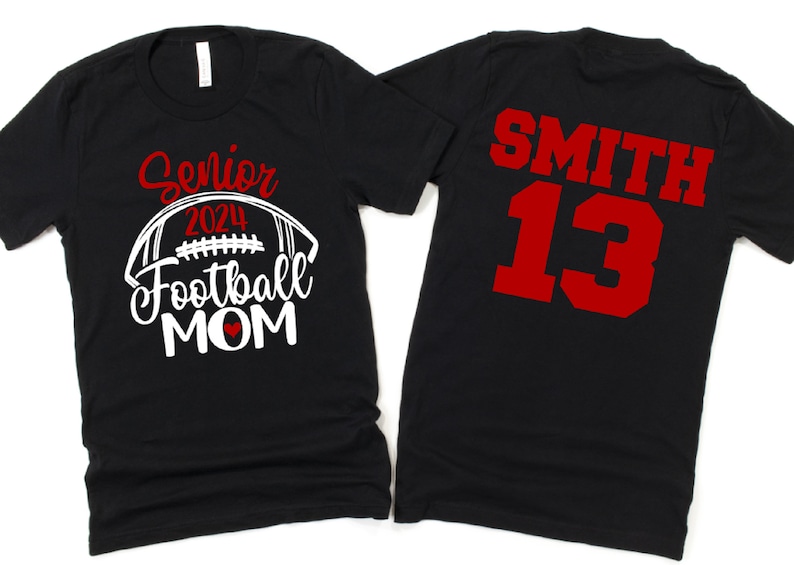 Op de afbeelding: Twee zwarte T-shirts. E&eacute;n shirt zegt "Senior 2024 Football Mom" met een witte voetbal en een rood hart. Het andere shirt heeft "SMITH 13" in rood op de achterkant.
