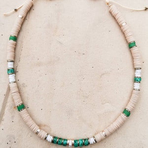 May include: A white and green beaded necklace with gold accents. The necklace is made of round beads and has a simple clasp.
