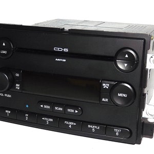 May include: Black car stereo with buttons labeled "LOAD", "CD", "AM", "FM", "MUTE", "MENU", "AUX", "SEEK", "SCAN", "SHUFFLE", and "TEXT". The stereo has a digital display and is labeled "CD-6" and "MP3".