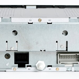May include: Rear view of a silver car stereo with two black connectors and a silver antenna connector.