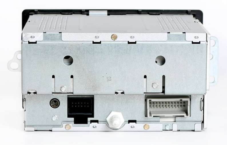 May include: Rear view of a silver car stereo with two black connectors and a silver antenna connector.