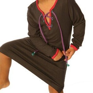May include: A dark gray children's dress with long sleeves and a lace-up neckline. The neckline features red and purple laces. The dress has a relaxed fit and falls to the knees.  The fabric appears soft and comfortable. The dress is suitable for casual wear.