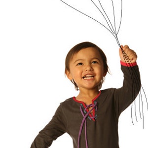 May include: A child holding a bunch of colourful balloons. The balloons are red, green, yellow, purple, blue, and orange. The child is wearing a dark grey dress with red and purple accents.