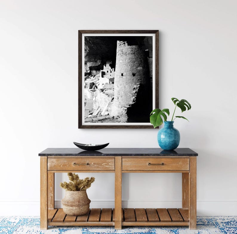 Puede incluir: Fotograf&iacute;a en blanco y negro de una vivienda en un acantilado en una cueva. La vivienda est&aacute; hecha de piedra y tiene una torre redonda. La fotograf&iacute;a est&aacute; enmarcada en un marco de madera oscura.