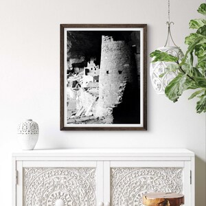 Puede incluir: Fotograf&iacute;a en blanco y negro de una vivienda en un acantilado en una cueva. La vivienda est&aacute; hecha de piedra y tiene varios niveles. La fotograf&iacute;a est&aacute; enmarcada en un marco de madera oscura.