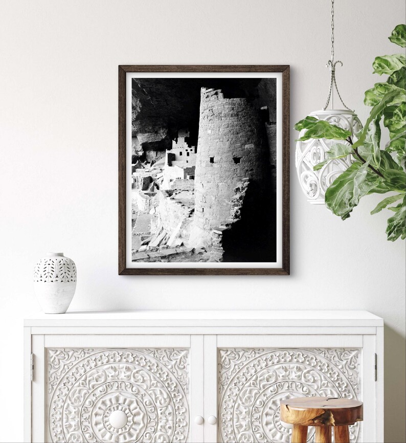 Puede incluir: Fotograf&iacute;a en blanco y negro de una vivienda en un acantilado en una cueva. La vivienda est&aacute; hecha de piedra y tiene varios niveles. La fotograf&iacute;a est&aacute; enmarcada en un marco de madera oscura.