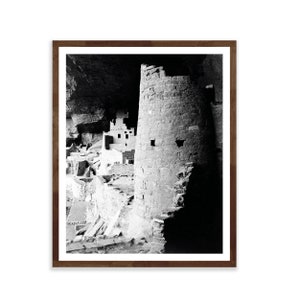 Puede incluir: Fotograf&iacute;a en blanco y negro de una vivienda en un acantilado en una cueva. La vivienda est&aacute; hecha de piedra y tiene una torre en el centro. La fotograf&iacute;a est&aacute; tomada desde un &aacute;ngulo bajo, mirando hacia arriba a la vivienda.