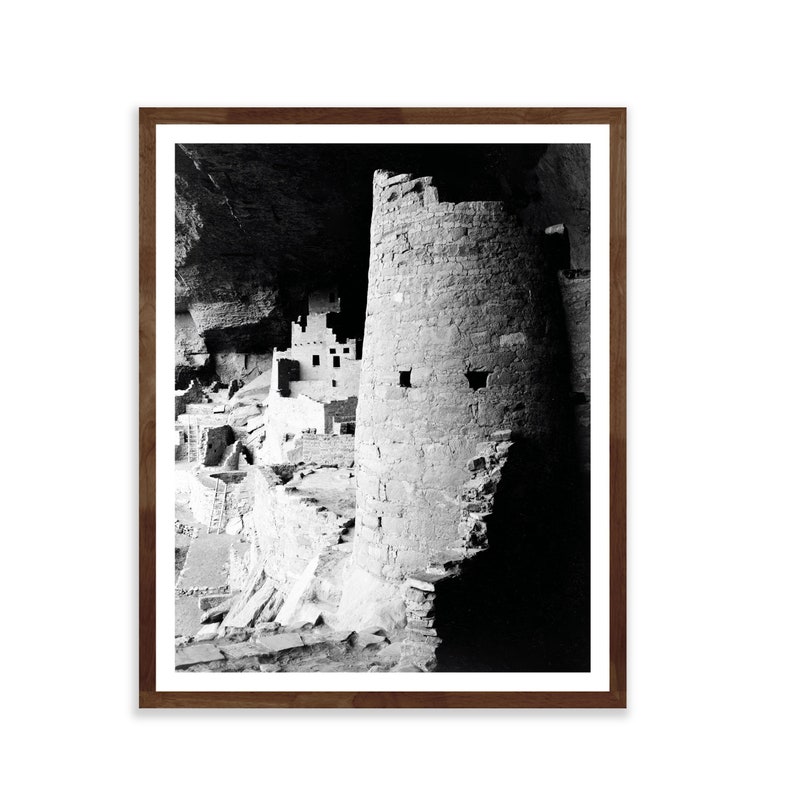 Puede incluir: Fotograf&iacute;a en blanco y negro de una vivienda en un acantilado en una cueva. La vivienda est&aacute; hecha de piedra y tiene una torre en el centro. La fotograf&iacute;a est&aacute; tomada desde un &aacute;ngulo bajo, mirando hacia arriba a la vivienda.