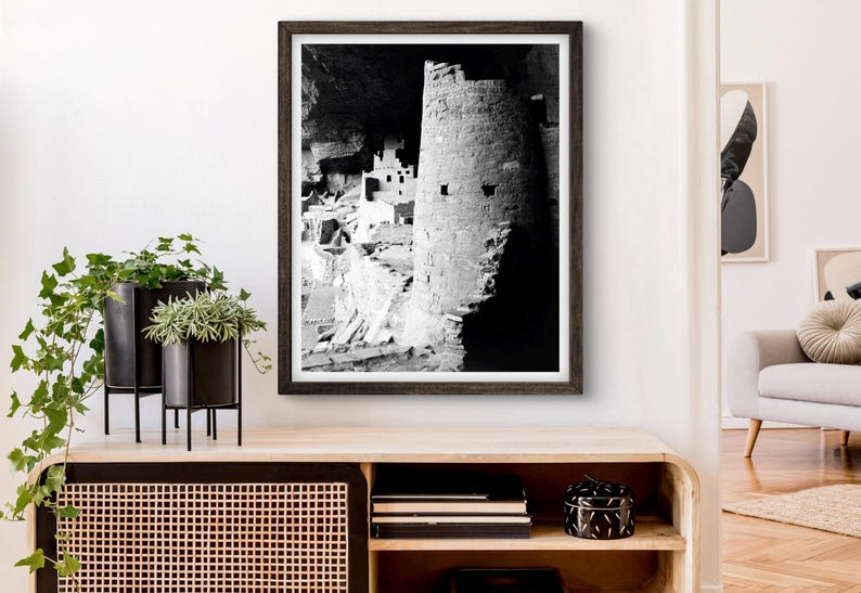 Puede incluir: Fotograf&iacute;a en blanco y negro de una vivienda en un acantilado en una cueva. La vivienda est&aacute; hecha de piedra y tiene una torre redonda. La fotograf&iacute;a est&aacute; enmarcada en un marco de madera oscura.