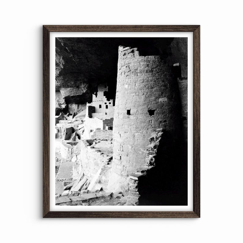 Puede incluir: Fotograf&iacute;a en blanco y negro de una vivienda en un acantilado en una cueva. La vivienda est&aacute; hecha de piedra y tiene una torre en primer plano. La torre est&aacute; parcialmente a la sombra, y el resto de la vivienda est&aacute; a la luz.