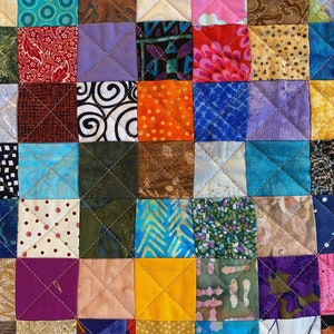 May include: A colourful quilt made of many different fabric squares, each with a unique pattern. The quilt is sewn together in a grid pattern, with each square being a different colour and design. The quilt is a beautiful example of patchwork quilting.
