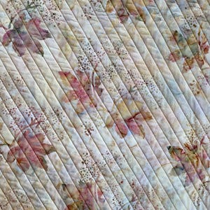 May include: A white fabric with a diagonal pattern of brown and pink leaves. The fabric has a subtle texture and a faded look.