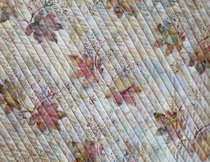 May include: A white fabric with a diagonal pattern of brown and pink leaves. The fabric has a subtle texture and a faded look.