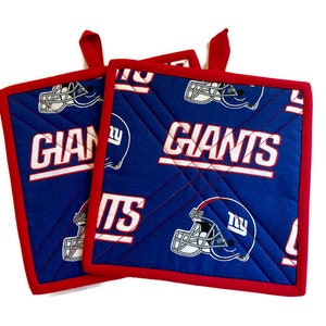 May include: A pair of red and blue quilted pot holders featuring the New York Giants logo and the word "Giants" repeated on the fabric.