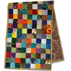 May include: A colourful patchwork table runner with a tan border. The runner is made of many different fabrics, each with a unique pattern. The runner is approximately 35 cm wide and 183 cm long.