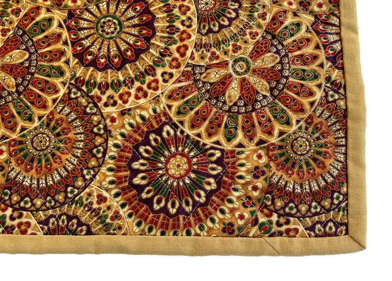 May include: A quilted fabric with a repeating pattern of colourful, intricate mandala designs. The fabric has a tan border.