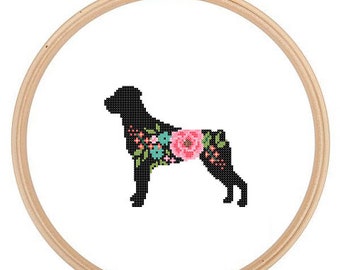 Könnte beinhalten: Eine schwarze Silhouette eines Hundes mit floralen Details in Rosa, Blau und Grün. Der Hund ist in einem hölzernen Stickrahmen gerahmt.